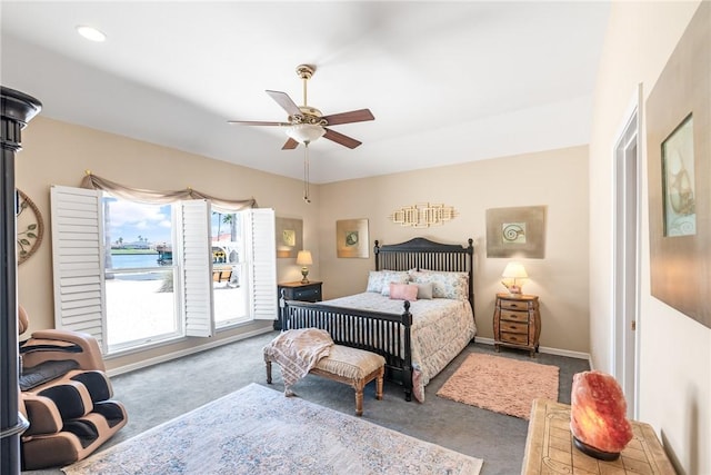 carpeted bedroom featuring ceiling fan, a water view, and baseboards