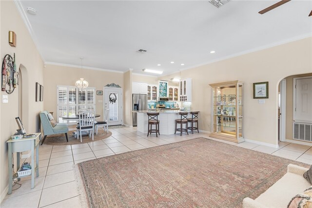 tiled living room featuring ornamental molding and ceiling fan with notable chandelier