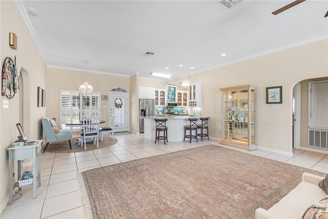 living area with light tile patterned floors, arched walkways, a ceiling fan, crown molding, and baseboards