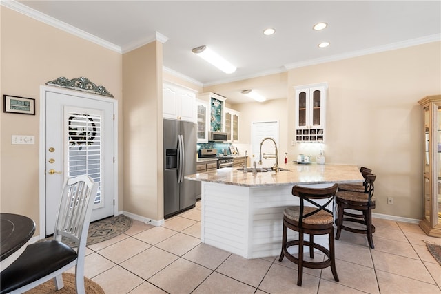 kitchen with stainless steel appliances, kitchen peninsula, sink, ornamental molding, and light tile patterned flooring