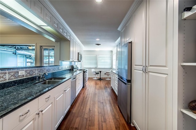 419 Peerman Pl, Corpus Christi, TX 78411 - kitchen with a sink, appliances with stainless steel finishes, dark wood-type flooring, decorative backsplash, and dark stone counters