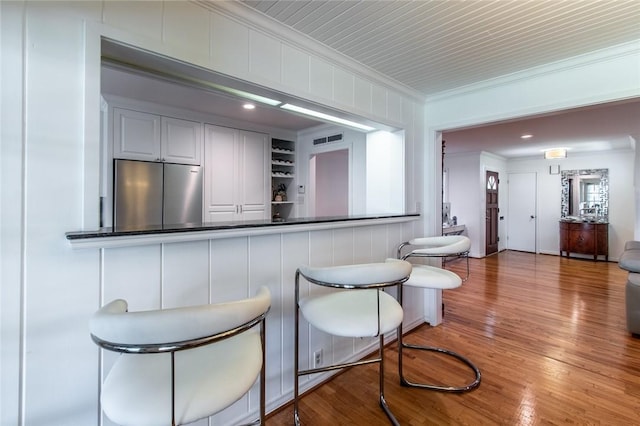419 Peerman Pl, Corpus Christi, TX 78411 - kitchen with stainless steel refrigerator, ornamental molding, wood finished floors, built in shelves, and a breakfast bar area