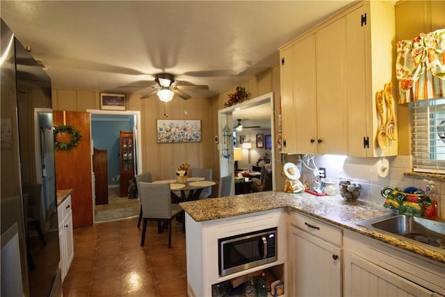 905 E Randall St, Beeville, TX 78102 - kitchen with a sink, a peninsula, fridge, stainless steel microwave, and a ceiling fan
