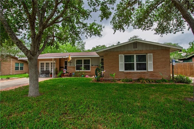 905 E Randall St, Beeville, TX 78102 - ranch-style home with board and batten siding, brick siding, fence, a front lawn, and concrete driveway