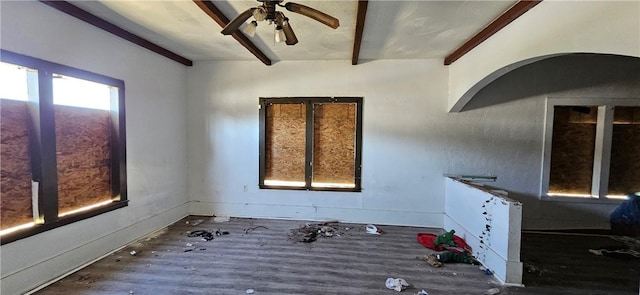 empty room with a ceiling fan, beam ceiling, and wood finished floors