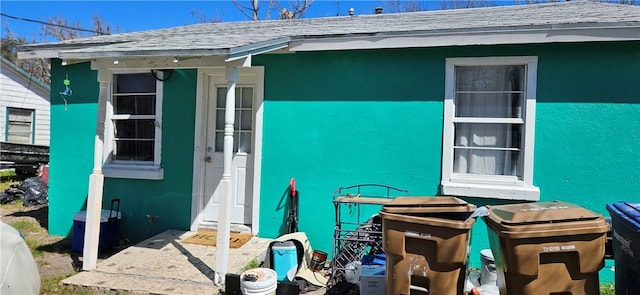 exterior space featuring roof with shingles and stucco siding