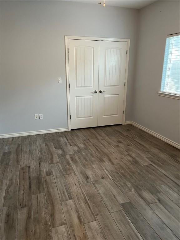 unfurnished bedroom with wood finished floors, baseboards, and a closet