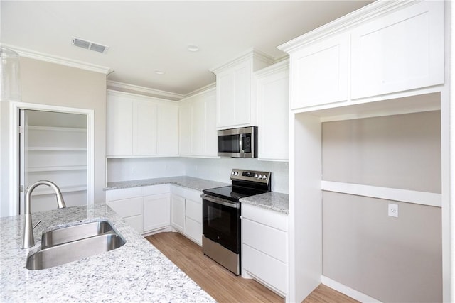 6214 Sadie St, Corpus Christi, TX 78415 - kitchen featuring stainless steel appliances, white cabinets, light stone countertops, light wood-style floors, and ornamental molding