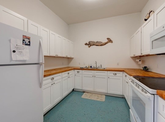 kitchen featuring white cabinets, white appliances, sink, and butcher block countertops