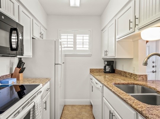 kitchen featuring white cabinetry, light stone counters, sink, and white appliances