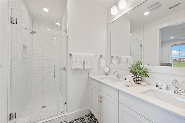 bathroom with double vanity, visible vents, a stall shower, and a sink