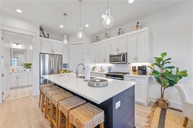 kitchen with a sink, a kitchen bar, appliances with stainless steel finishes, and white cabinets