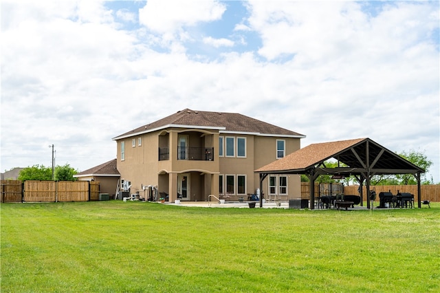 rear view of property with a balcony, a yard, a gazebo, and a patio area