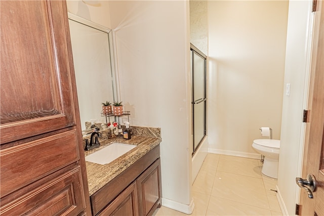 bathroom featuring toilet, vanity, tile patterned flooring, and a shower with door