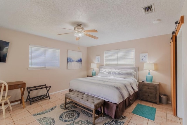 122 Palm Dr, Rockport, TX 78382 - bedroom with tile patterned flooring, visible vents, a textured ceiling, and a barn door