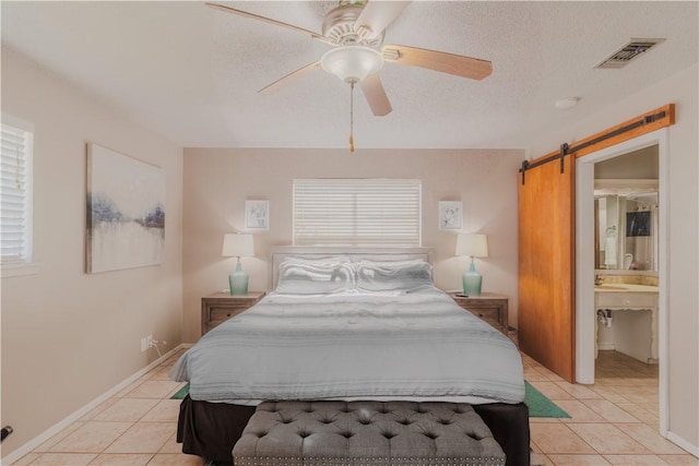 122 Palm Dr, Rockport, TX 78382 - bedroom with a barn door, light tile patterned floors, visible vents, and a textured ceiling