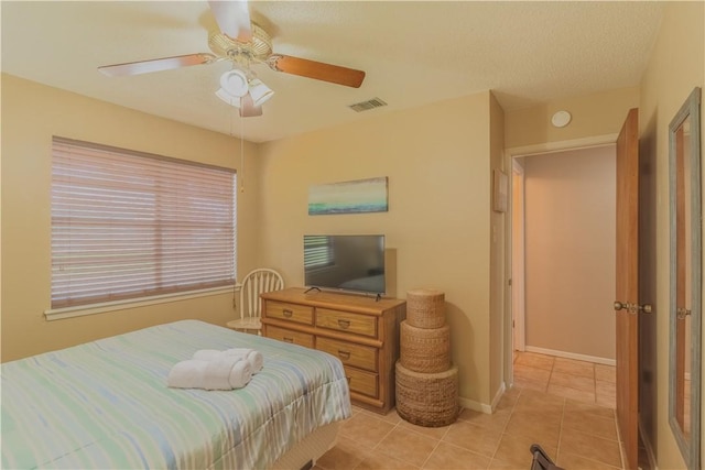 122 Palm Dr, Rockport, TX 78382 - bedroom with light tile patterned flooring, baseboards, visible vents, and ceiling fan