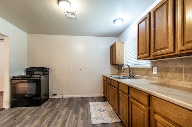 5921 Riley Dr, Corpus Christi, TX 78412 - kitchen with black / electric stove, brown cabinetry, dark wood finished floors, light countertops, and backsplash