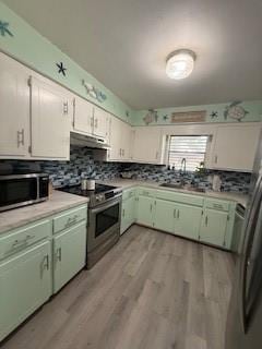 1638 W Palm Dr, Aransas Pass, TX 78336 - kitchen with appliances with stainless steel finishes, green cabinetry, under cabinet range hood, tasteful backsplash, and light countertops