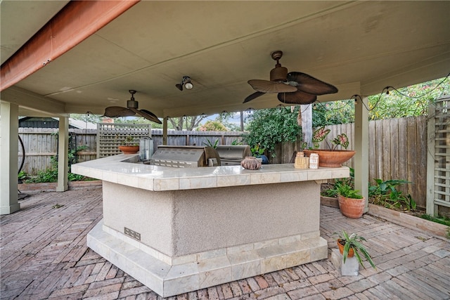 view of patio / terrace with exterior bar, area for grilling, and ceiling fan