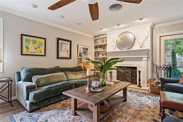 living room featuring ceiling fan, hardwood / wood-style flooring, ornamental molding, and a fireplace