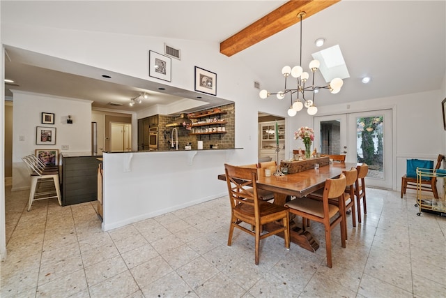 dining room featuring sink, french doors, a chandelier, and lofted ceiling with skylight