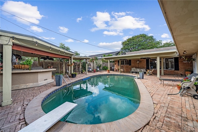 view of swimming pool featuring a diving board, ceiling fan, and a patio