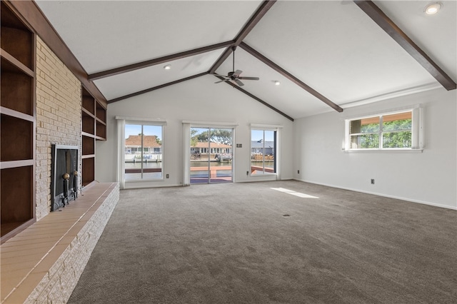 unfurnished living room with a brick fireplace, ceiling fan, lofted ceiling with beams, and carpet