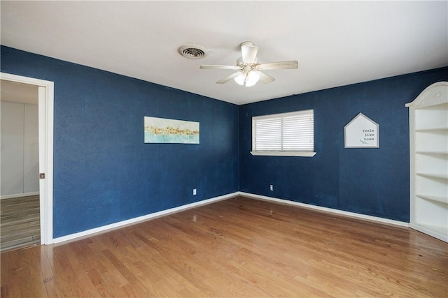 unfurnished room with a ceiling fan, baseboards, visible vents, and wood finished floors