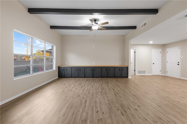 unfurnished room with ceiling fan, beam ceiling, and light wood-type flooring