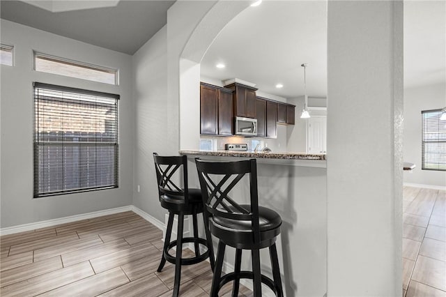 1012 Santa Catalina St, Portland, TX 78374 - kitchen with stainless steel microwave, a breakfast bar area, dark brown cabinets, baseboards, and recessed lighting