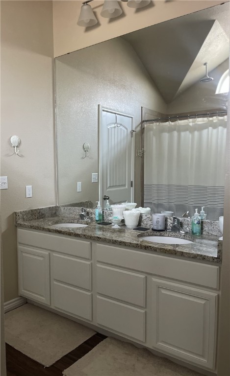 bathroom featuring walk in shower, lofted ceiling, and vanity