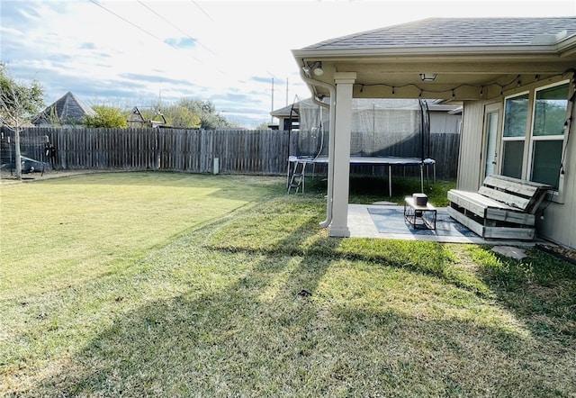 view of yard with a trampoline and a patio area