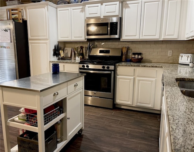 kitchen featuring white cabinetry, stainless steel appliances, dark hardwood / wood-style flooring, and tasteful backsplash