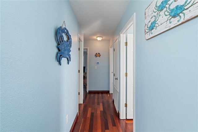corridor with wood finished floors and baseboards