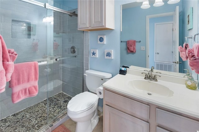 bathroom with toilet, vanity, and a stall shower
