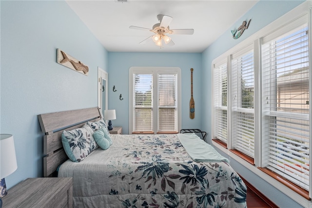 bedroom featuring multiple windows, hardwood / wood-style flooring, and ceiling fan