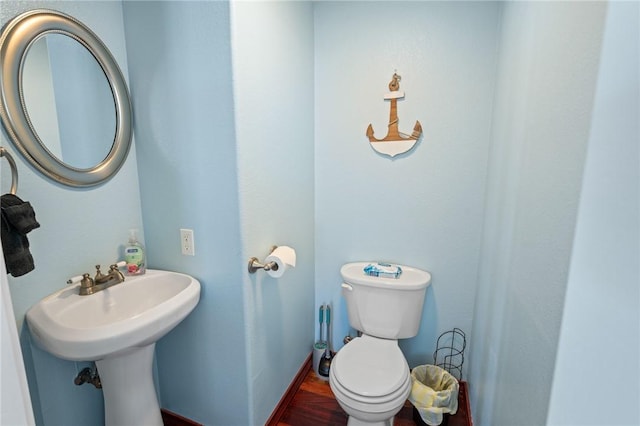 half bathroom with toilet and wood finished floors