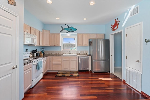 kitchen with appliances with stainless steel finishes, a sink, dark wood-style flooring, recessed lighting, and dark countertops
