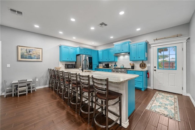 230 Valerie St, Corpus Christi, TX 78418 - kitchen with blue cabinetry, stainless steel appliances, a breakfast bar area, a sink, and dark wood-type flooring