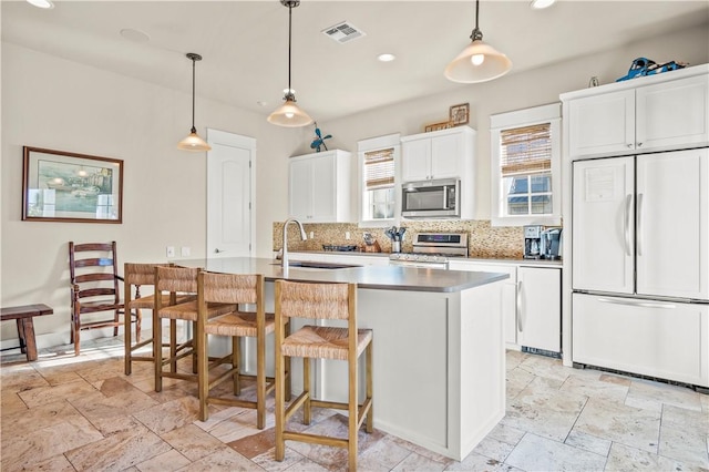 kitchen with a kitchen island with sink, white cabinetry, sink, and appliances with stainless steel finishes