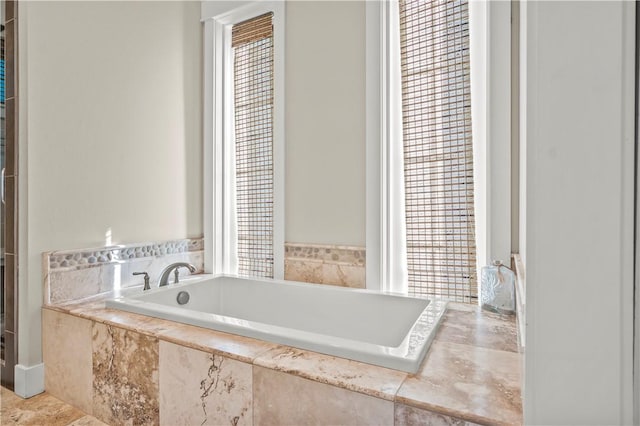 bathroom featuring a healthy amount of sunlight and tiled tub