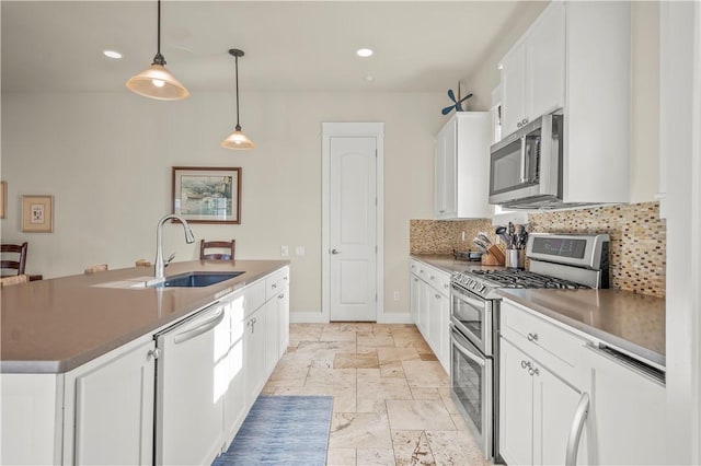 kitchen with pendant lighting, a kitchen island with sink, white cabinets, decorative backsplash, and appliances with stainless steel finishes