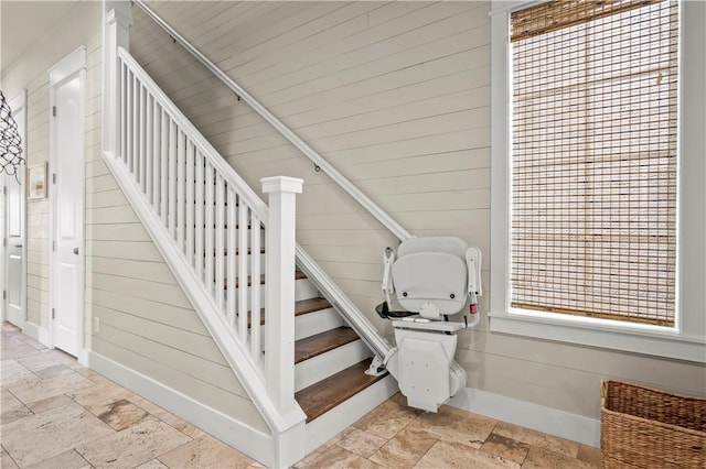 stairway with wooden walls, wood ceiling, and vaulted ceiling