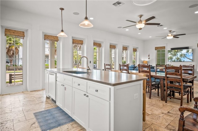 104 Still Water Dr, Port Aransas, TX 78373 - kitchen featuring a sink, stone tile flooring, ceiling fan, an island with sink, and white cabinets