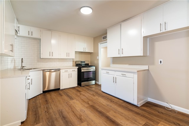 kitchen with white cabinets, appliances with stainless steel finishes, wood-type flooring, and sink