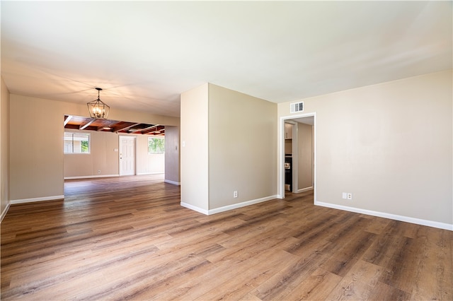 spare room featuring an inviting chandelier and hardwood / wood-style flooring