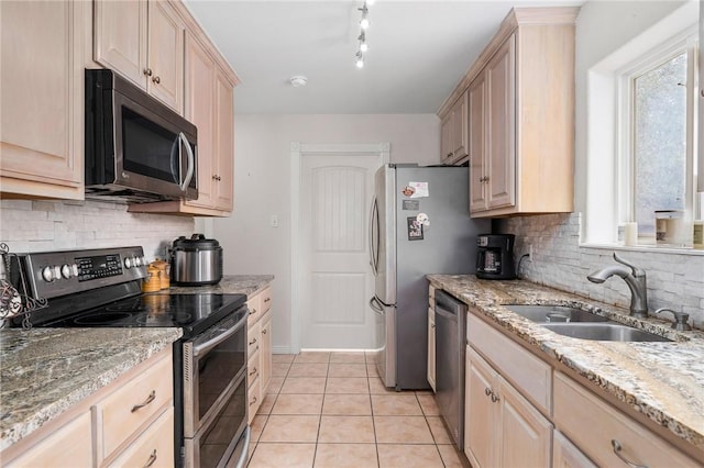 kitchen featuring light brown cabinetry, sink, light tile patterned floors, stainless steel appliances, and light stone countertops