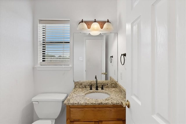 bathroom featuring vanity, a healthy amount of sunlight, and toilet