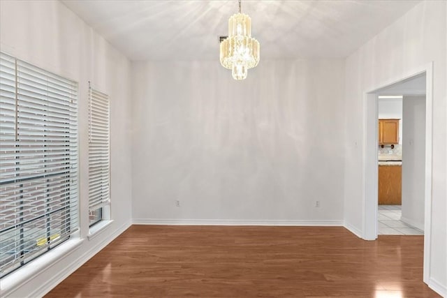 empty room with a chandelier and hardwood / wood-style flooring